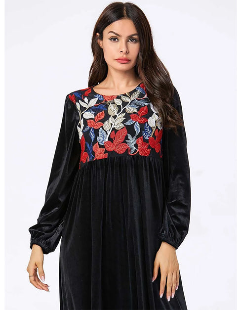 A flowing black or emerald green velvet abaya with delicate gold embroidery around the cuffs and neckline