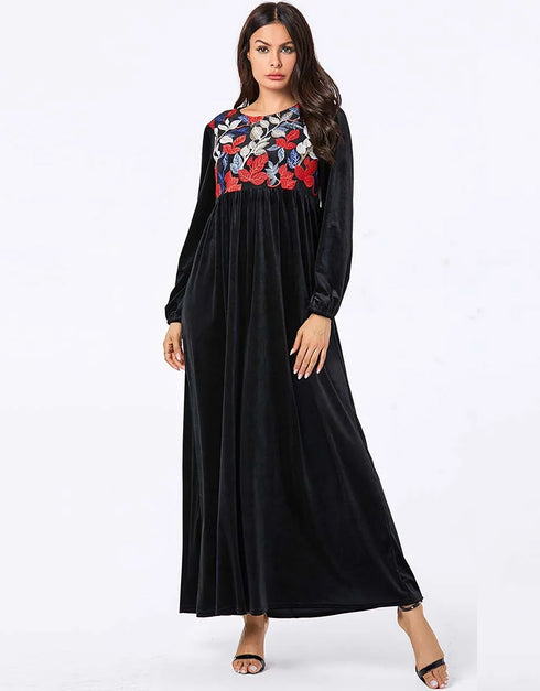 A flowing black or emerald green velvet abaya with delicate gold embroidery around the cuffs and neckline